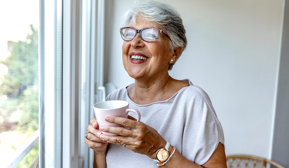 pensioner_smiling_out_window_with_coffee_cup