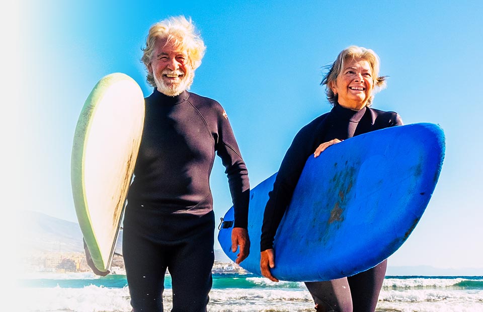 seniors on beach with surfboards smiling