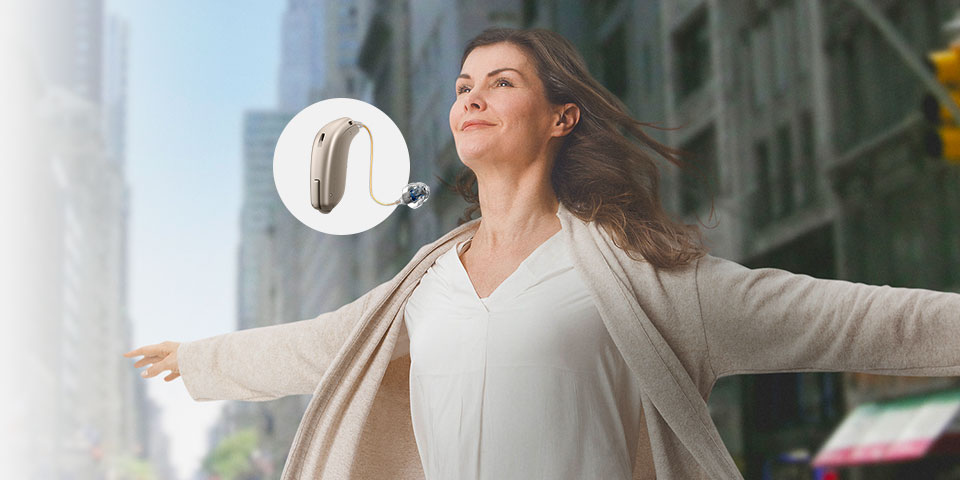 Image of a lady smiling and a Oticon Opn hearing aid