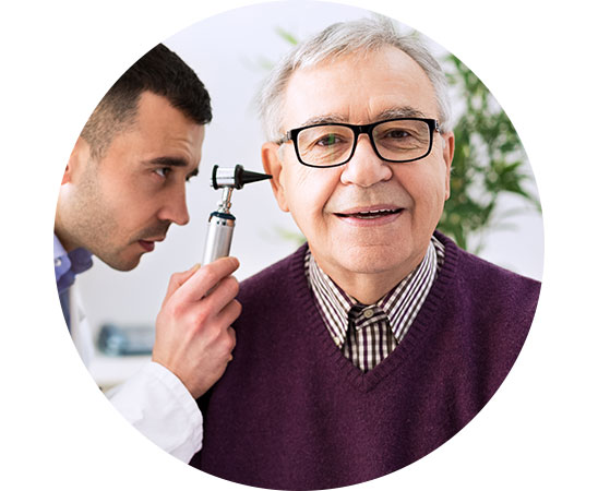 Image shows audiologist examing ear of a man whose hearing loss was caused by aging